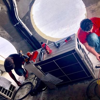 Two technicians installing an outdoor condenser — Affordable Air Service