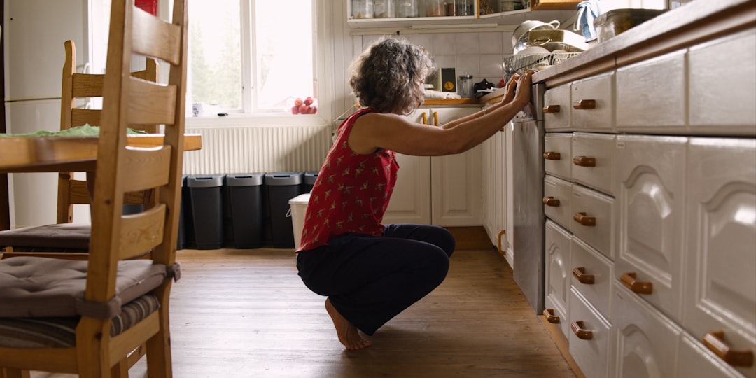 Blog 5 homeowner inspecting a leaky kitchen sink under the cabinet - when should you call a plumber vs diy